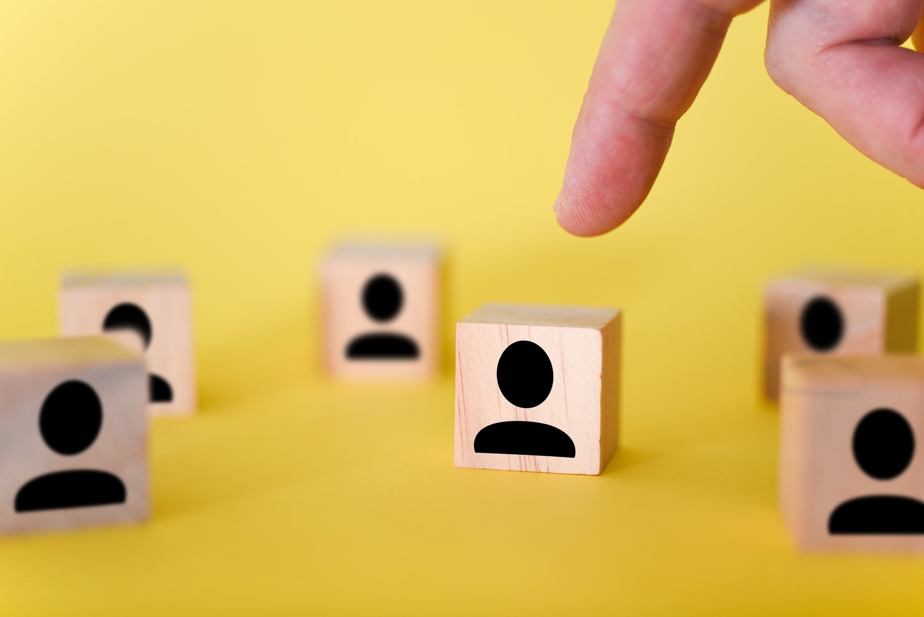 The search for new managers to lead organizations and teams is shown using wooden cubes, on a yellow background.